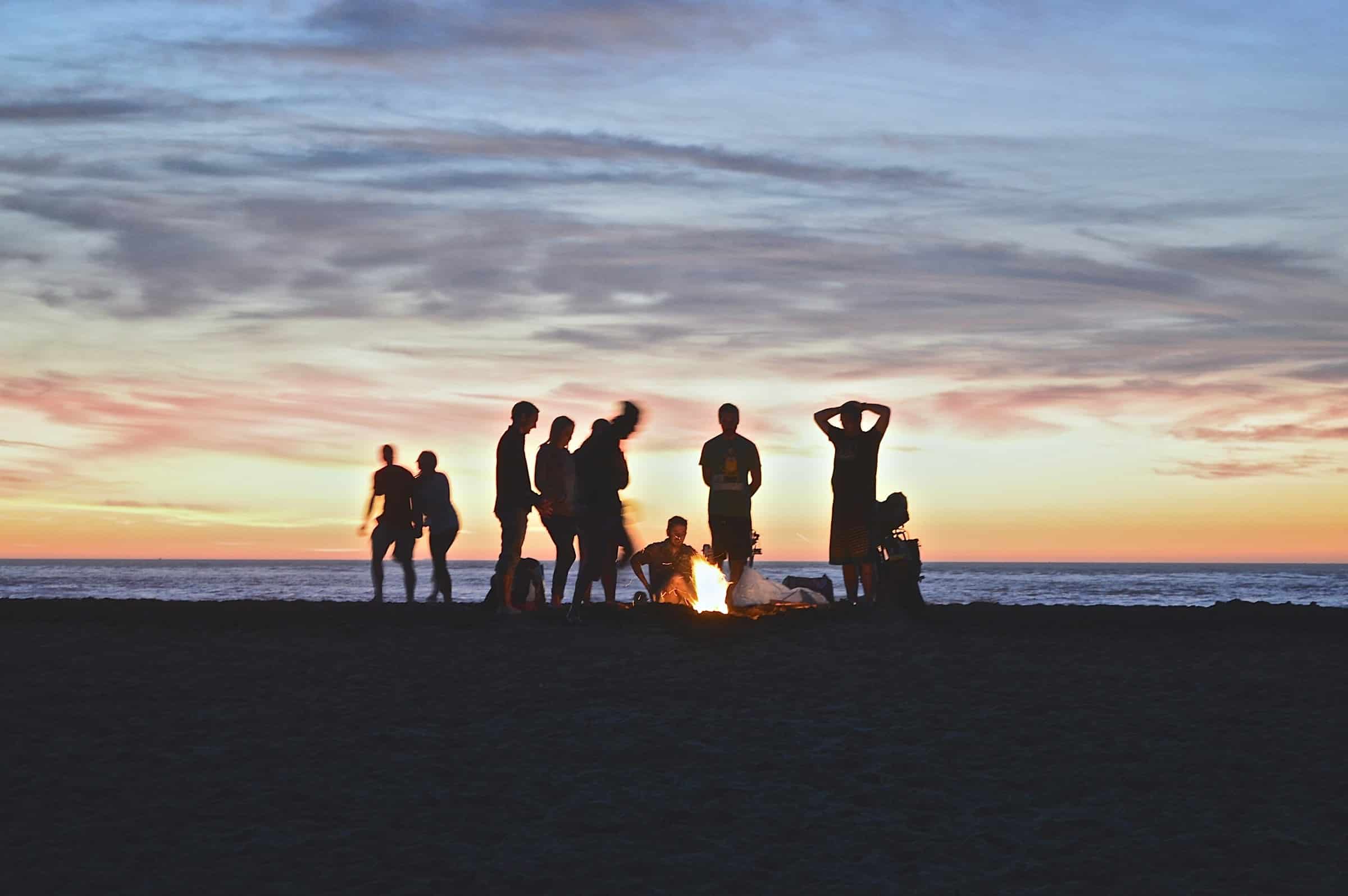 Men building connection at sunset bonfire on the beach